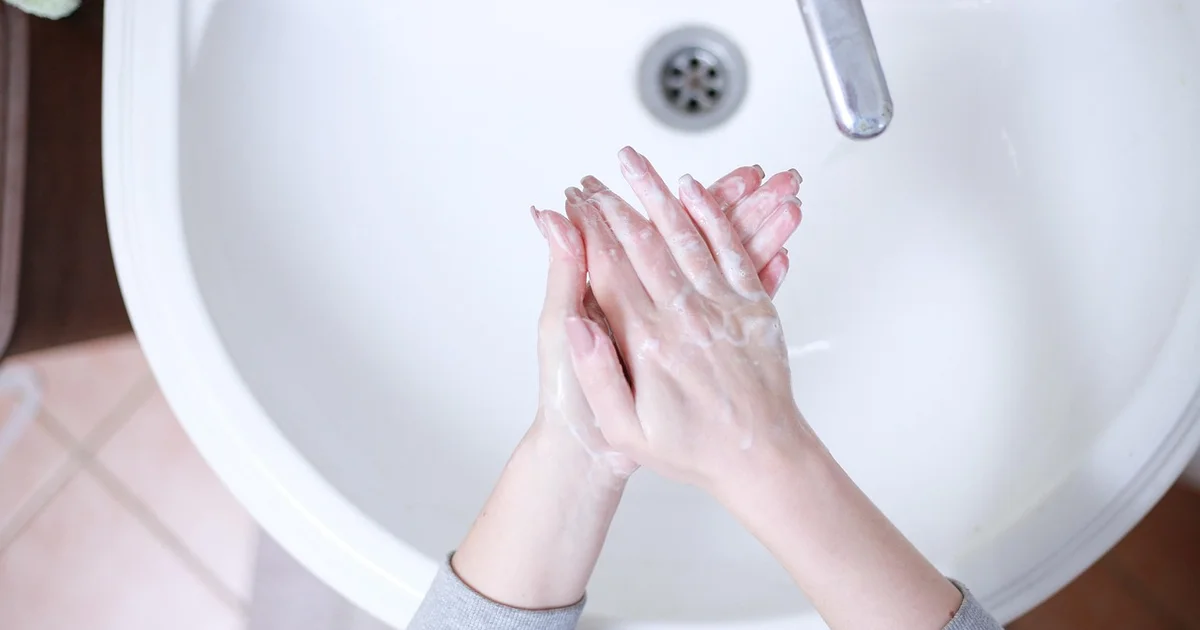 세면대 앞에서 두 손에 비누 거품을 내어 문질러 씻고 있는 모습을 위에서 내려다본 사진